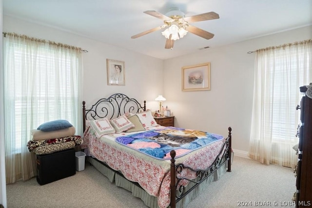 bedroom featuring multiple windows, light colored carpet, and ceiling fan