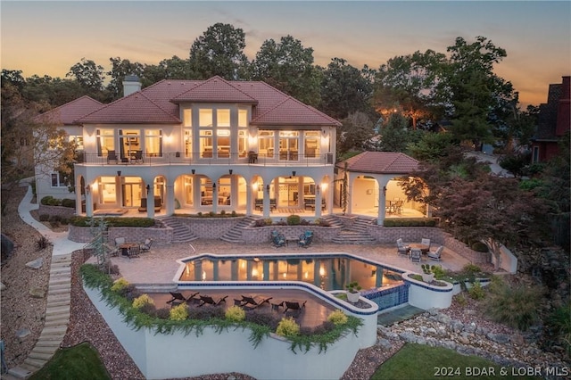 back house at dusk with a patio and a balcony