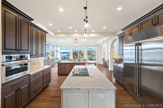 kitchen with hanging light fixtures, stainless steel appliances, dark brown cabinetry, and a kitchen island