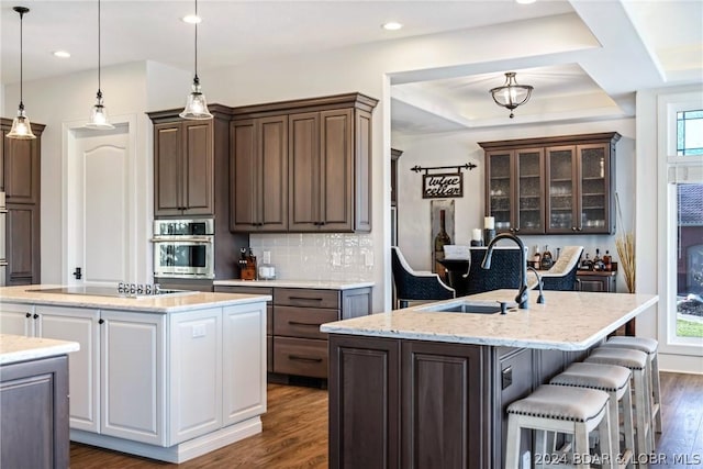 kitchen with black electric stovetop, decorative backsplash, white cabinets, and a kitchen island with sink