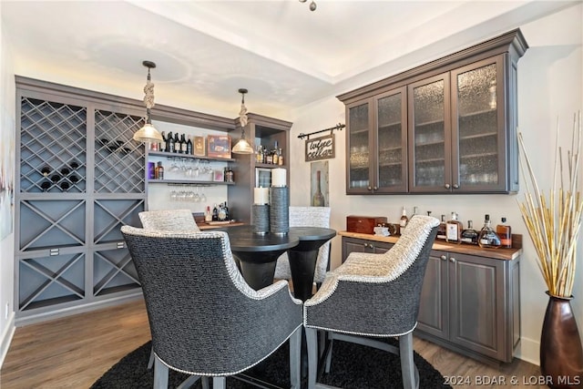 bar with hanging light fixtures, dark hardwood / wood-style flooring, and dark brown cabinetry