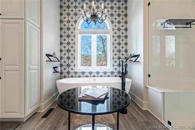 bathroom with a washtub, hardwood / wood-style floors, and an inviting chandelier