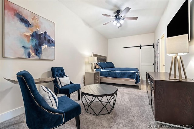 carpeted bedroom with ceiling fan and a barn door