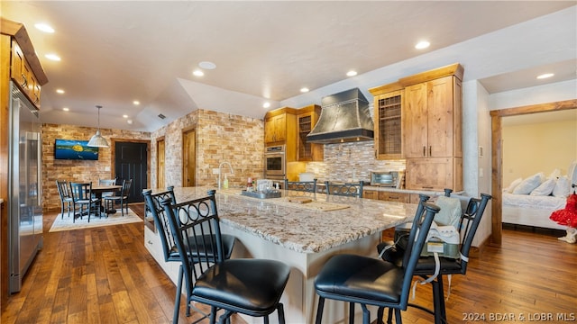 kitchen with dark hardwood / wood-style flooring, pendant lighting, a kitchen breakfast bar, and custom range hood