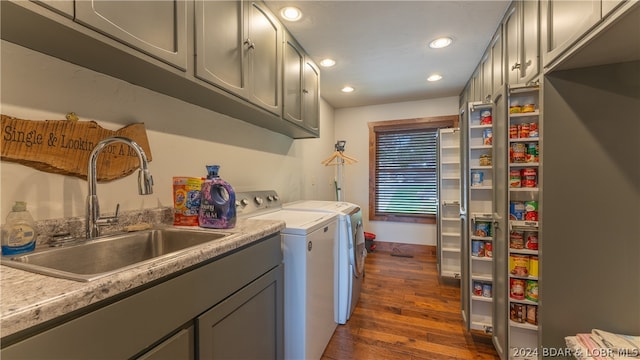 clothes washing area with cabinets, dark wood-type flooring, washing machine and clothes dryer, and sink