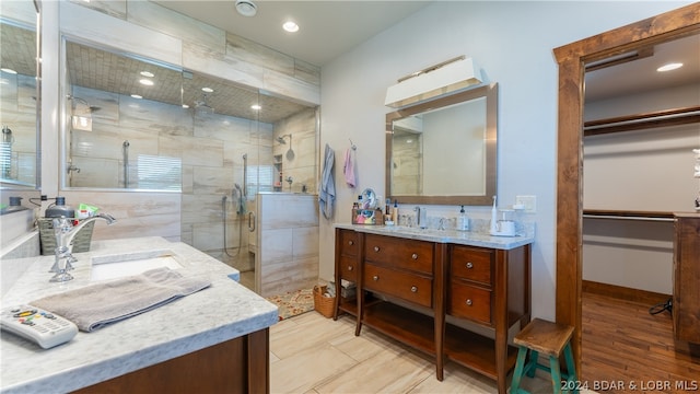 bathroom with a shower with shower door, vanity, and wood-type flooring