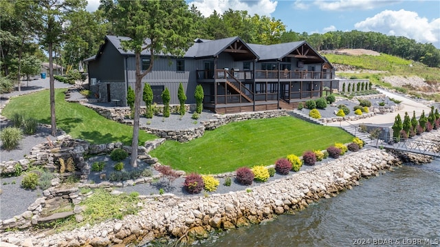 back of house with a lawn and a deck with water view