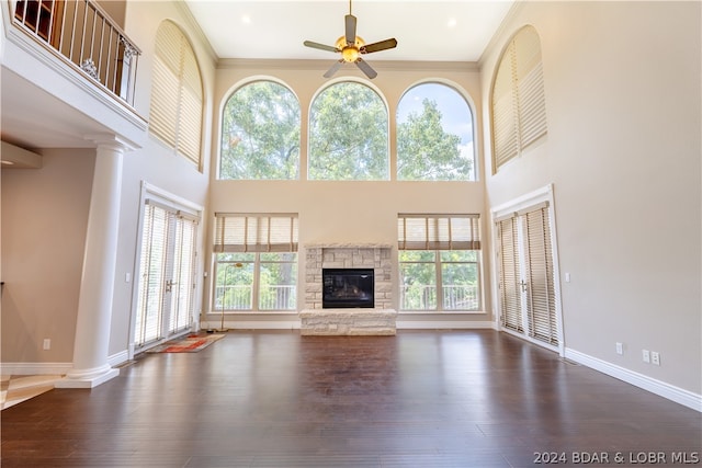 unfurnished living room featuring plenty of natural light, a stone fireplace, and dark hardwood / wood-style flooring