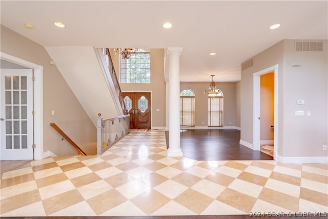 entrance foyer featuring an inviting chandelier, ornate columns, and light hardwood / wood-style floors