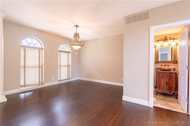 spare room featuring hardwood / wood-style flooring, sink, and an inviting chandelier