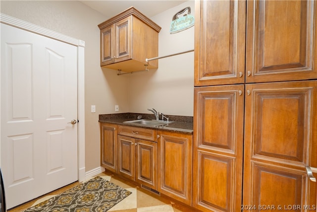 kitchen featuring light tile patterned flooring, sink, and dark stone counters