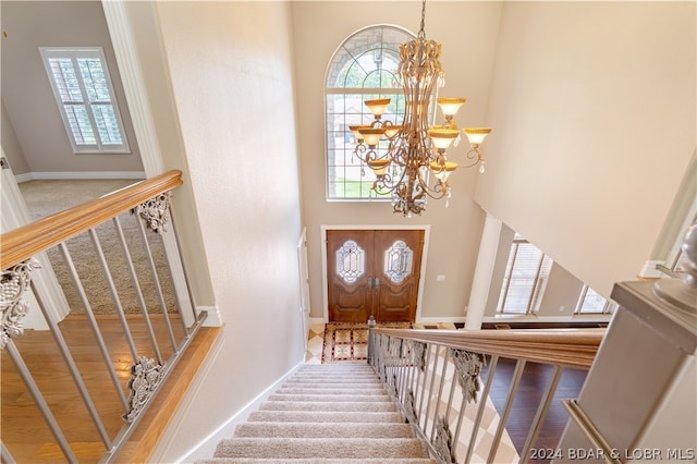 foyer featuring an inviting chandelier, a healthy amount of sunlight, a towering ceiling, and wood-type flooring