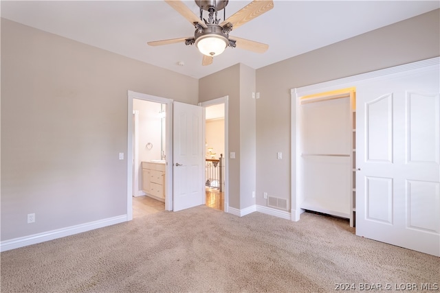 unfurnished bedroom featuring light carpet, ensuite bathroom, and ceiling fan