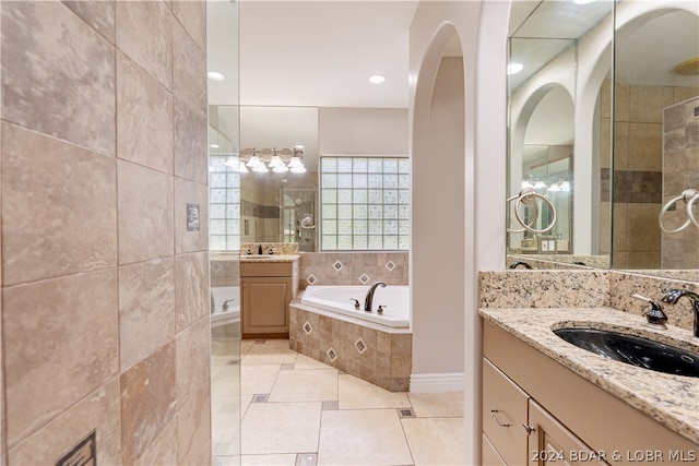 bathroom featuring tiled tub, tile patterned floors, and dual bowl vanity