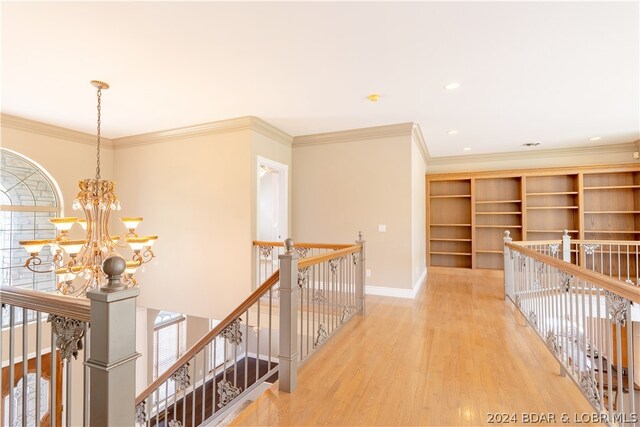 hallway with light hardwood / wood-style flooring, a chandelier, and ornamental molding