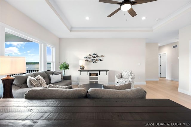 living room with a tray ceiling, light hardwood / wood-style flooring, and ceiling fan