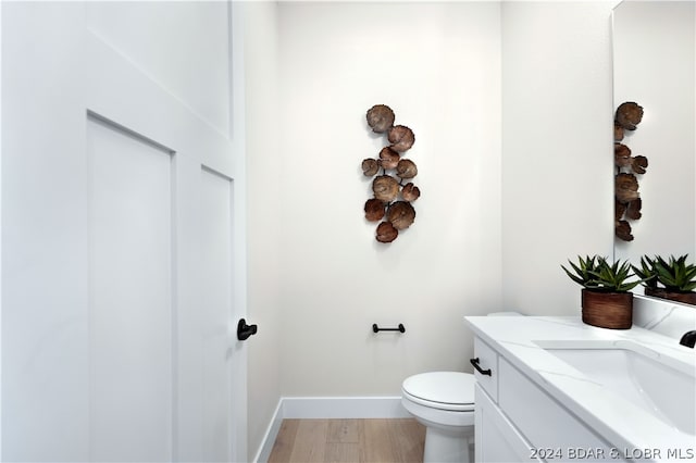 bathroom featuring toilet, vanity, and hardwood / wood-style flooring