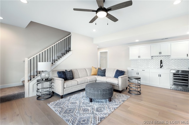 living room featuring ceiling fan, sink, beverage cooler, and light hardwood / wood-style floors