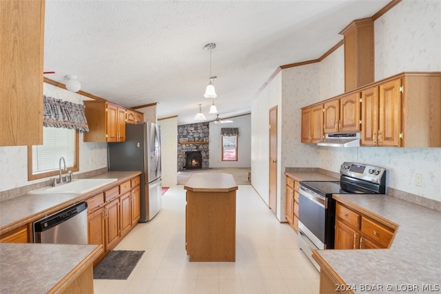 kitchen featuring pendant lighting, sink, crown molding, appliances with stainless steel finishes, and a stone fireplace