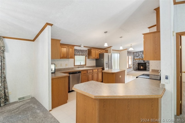 kitchen with a center island, hanging light fixtures, appliances with stainless steel finishes, kitchen peninsula, and a fireplace