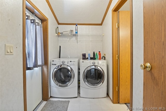 clothes washing area with ornamental molding, a textured ceiling, and washer and clothes dryer