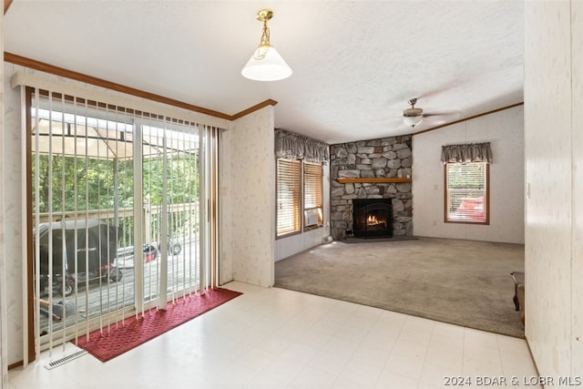 living room with a stone fireplace, a healthy amount of sunlight, light colored carpet, and a textured ceiling