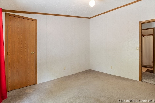 unfurnished room featuring crown molding, carpet flooring, vaulted ceiling, and a textured ceiling