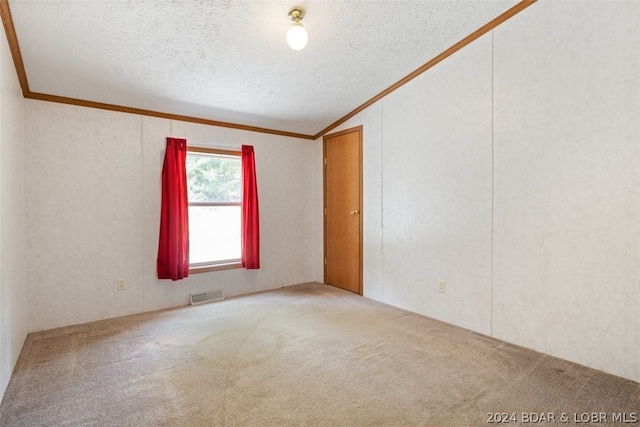 spare room featuring lofted ceiling, ornamental molding, carpet flooring, and a textured ceiling