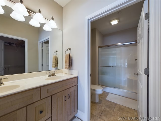 bathroom featuring vanity, a shower with shower door, tile patterned floors, and toilet