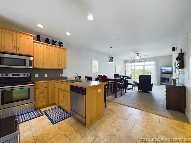 kitchen with sink, light tile patterned floors, stainless steel appliances, decorative light fixtures, and kitchen peninsula