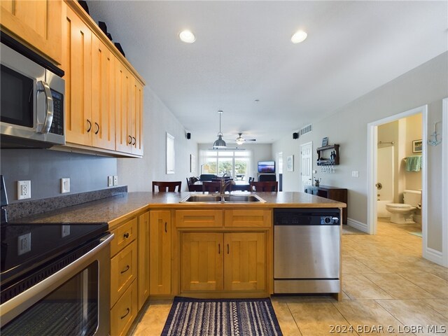 kitchen featuring stainless steel appliances, sink, kitchen peninsula, light tile patterned floors, and ceiling fan