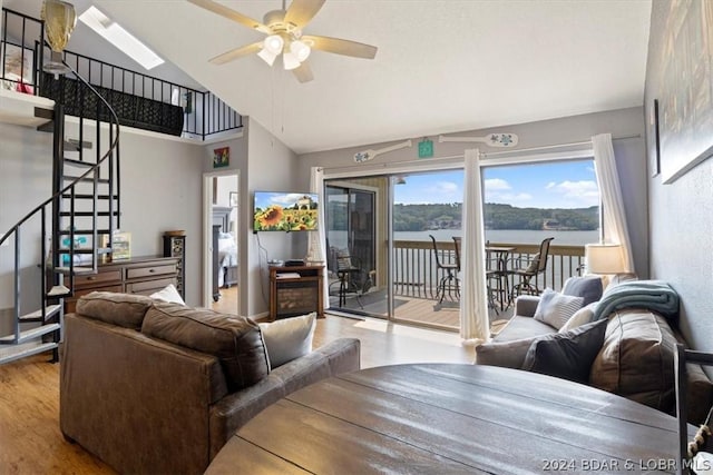 living room with ceiling fan, vaulted ceiling, and light wood-type flooring