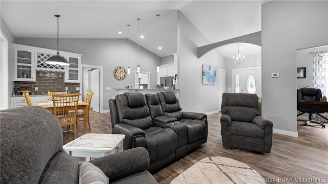 living room featuring high vaulted ceiling, an inviting chandelier, and dark hardwood / wood-style floors