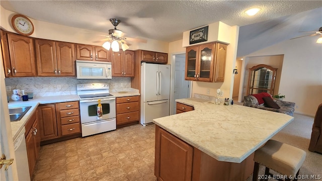 kitchen featuring a breakfast bar area, tasteful backsplash, white appliances, kitchen peninsula, and ceiling fan