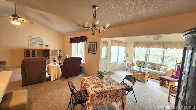 carpeted dining area featuring ceiling fan with notable chandelier, vaulted ceiling, and a textured ceiling