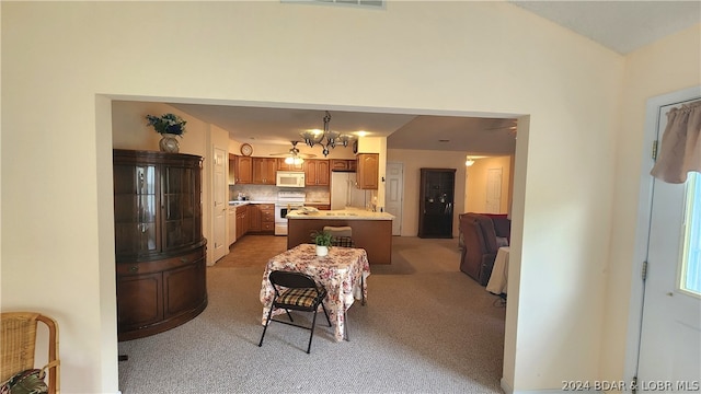 kitchen with a kitchen island, pendant lighting, decorative backsplash, light colored carpet, and white appliances