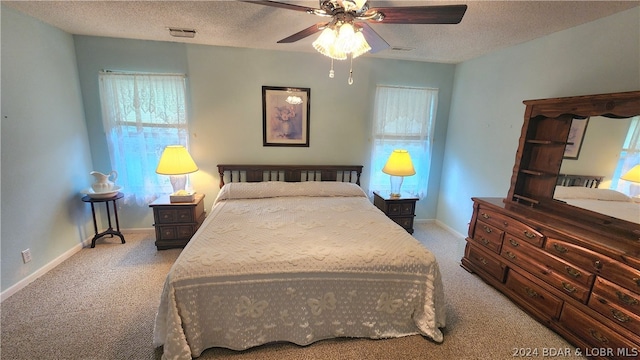 carpeted bedroom featuring ceiling fan and a textured ceiling