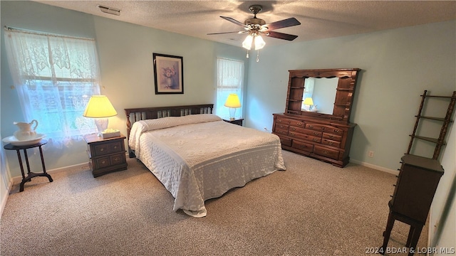 bedroom with multiple windows, ceiling fan, a textured ceiling, and carpet flooring