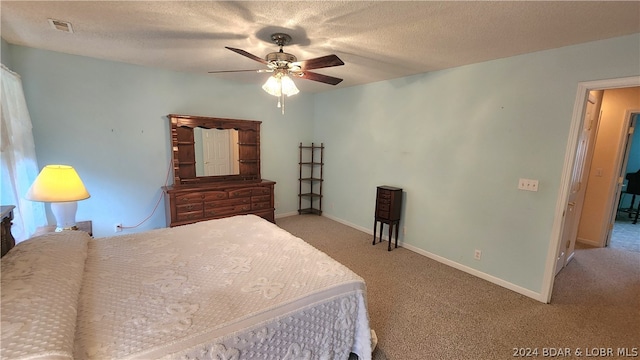 bedroom with ceiling fan, light colored carpet, and a textured ceiling