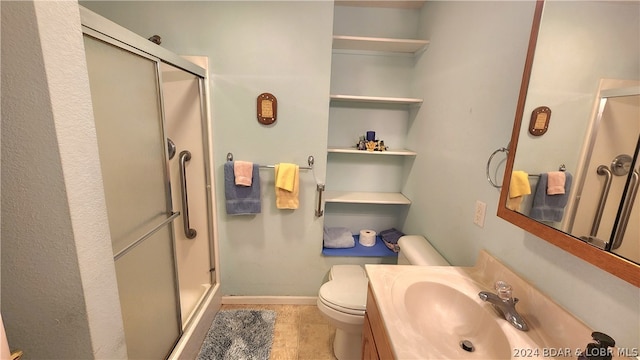 bathroom with vanity, toilet, tile patterned flooring, and a shower with door