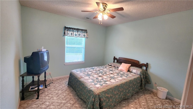 carpeted bedroom featuring ceiling fan and a textured ceiling