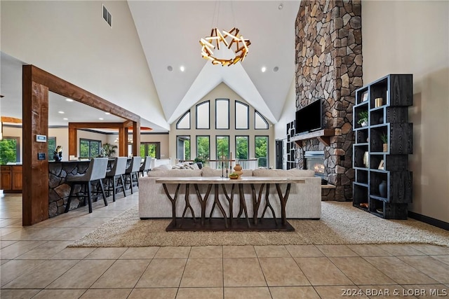 living room featuring a stone fireplace, a chandelier, light tile patterned floors, and high vaulted ceiling