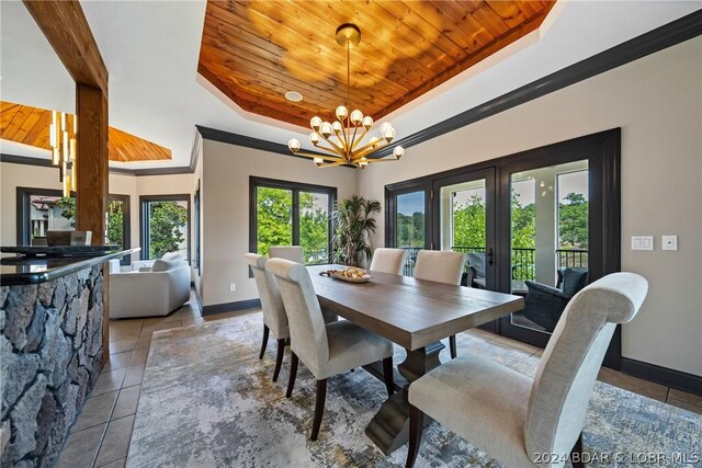 tiled dining area with wood ceiling, crown molding, an inviting chandelier, a tray ceiling, and french doors