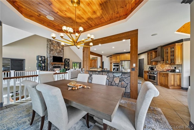 dining room featuring a stone fireplace, wood ceiling, light tile patterned floors, a raised ceiling, and a notable chandelier