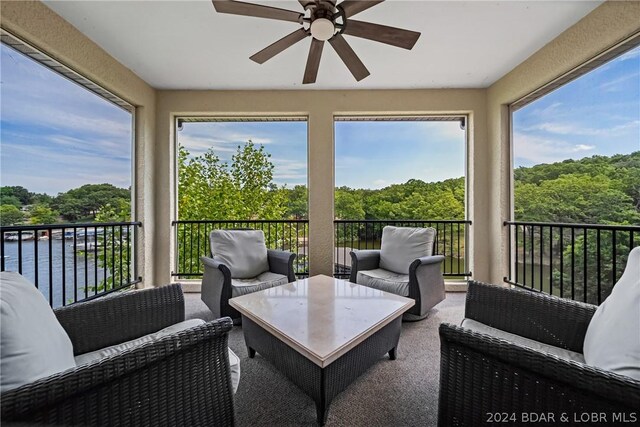 sunroom / solarium featuring a water view, ceiling fan, and a wealth of natural light