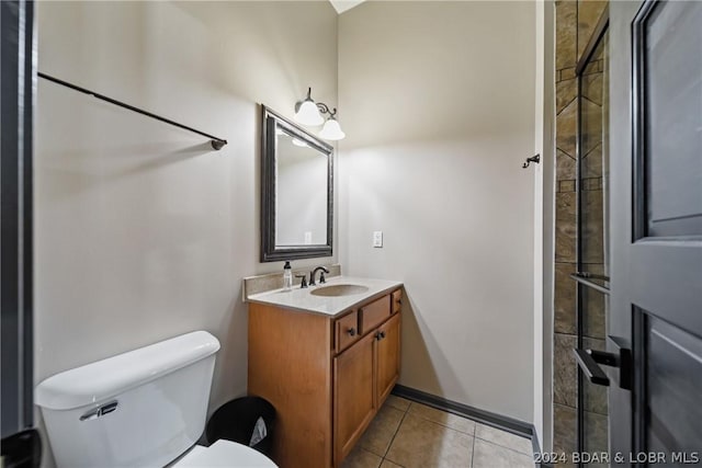 bathroom with tile patterned flooring, vanity, toilet, and tiled shower