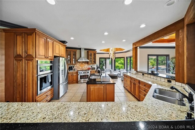 kitchen featuring stainless steel appliances, sink, wall chimney range hood, and kitchen peninsula