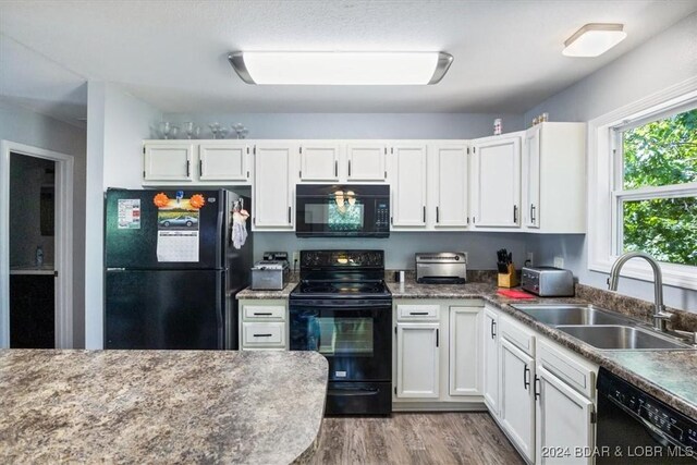 kitchen with white cabinetry, hardwood / wood-style flooring, black appliances, and sink