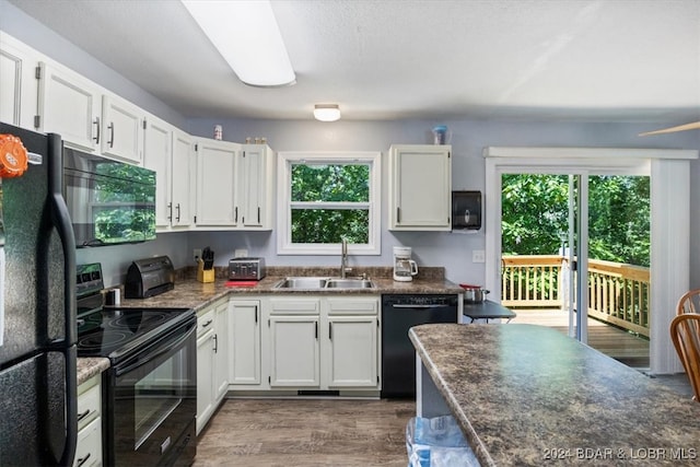 kitchen with sink, black appliances, a wealth of natural light, and dark wood-type flooring