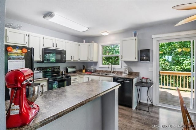 kitchen with sink, white cabinets, dark hardwood / wood-style flooring, and black appliances